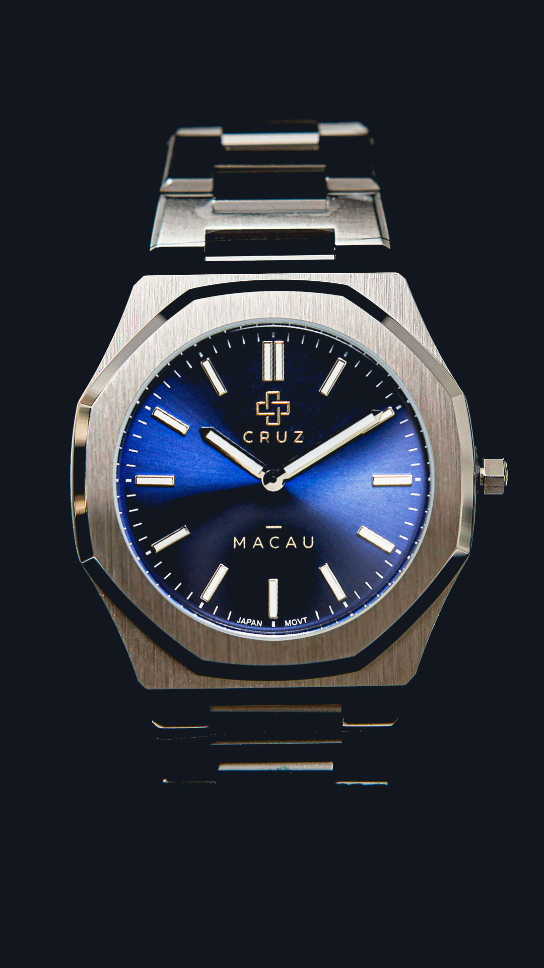 Cruz Watches Macau com mostrador azul, caixa prateada e pulseira de aço, sobre fundo escuro.